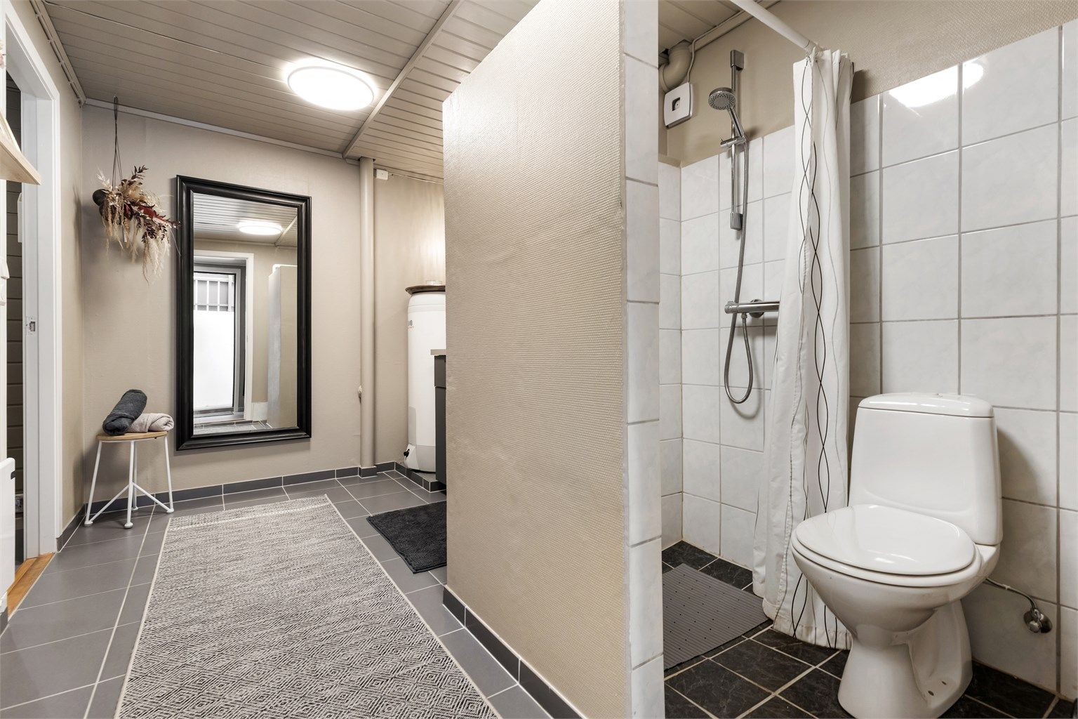 Badet har gulvstående toalett og dusjnisje.