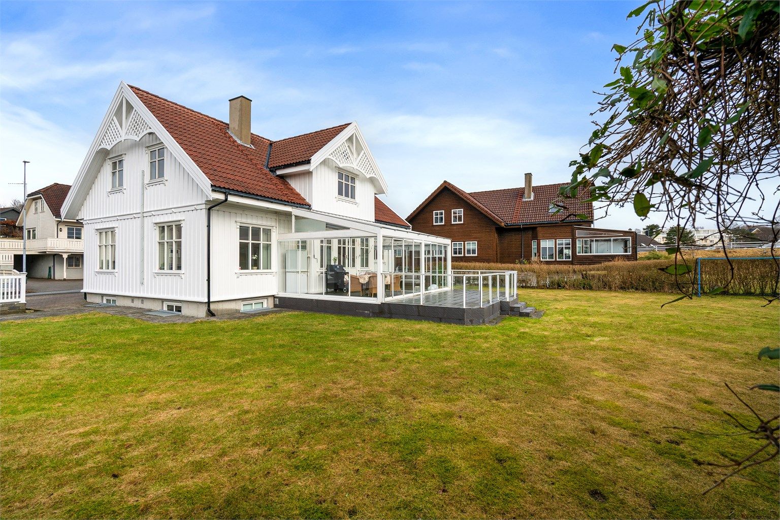 Tomten er pent opparbeidet med belegningsstein, plen og beplantning.