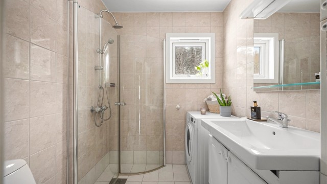 Badet er utstyrt med dusjhjørne, servantinnredning og opplegg for vaskemaskin.