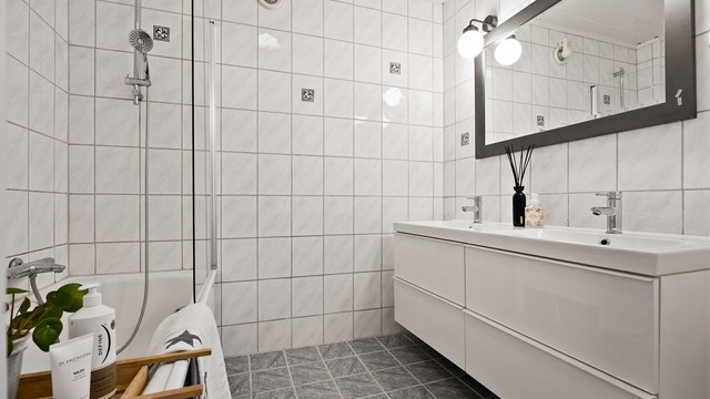 Bad i underetasjen med badekar, dusjløsning og dobbel servant.