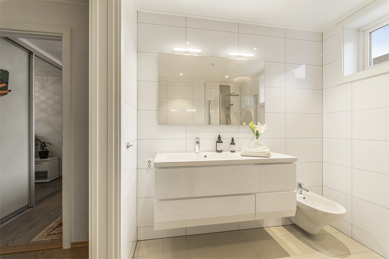 Badet er innredet med dusjhjørne, bidè, vegghengt toalett og servant i innredning