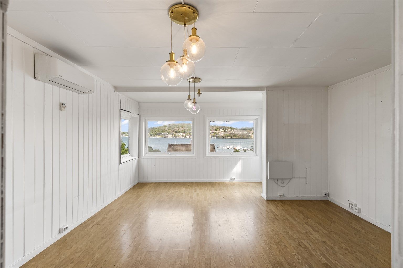 Stuen er lys og romslig, med vinduer som rammer inn utsikten mot sjøen.