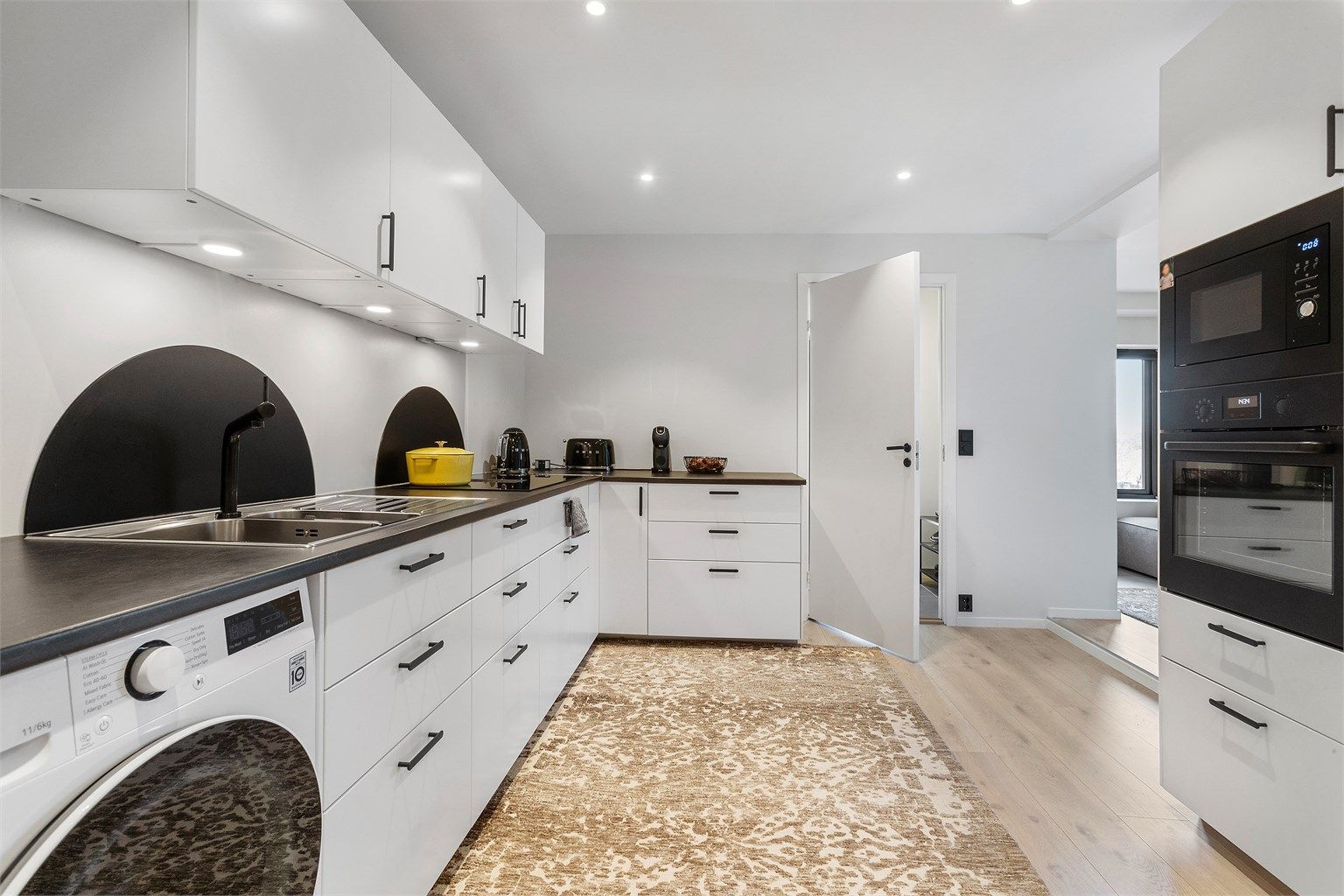 Kjøkkenet i hybelen er moderne og funksjonelt, med slette fronter og integrert stekeovn og mikrobølgeovn.