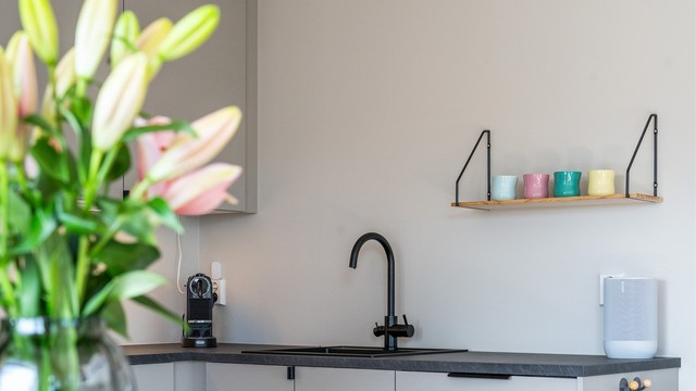 Kjøkkenet har en stilren innredning med glatte fronter, laminat benkeplate og integrerte hvitevarer.
