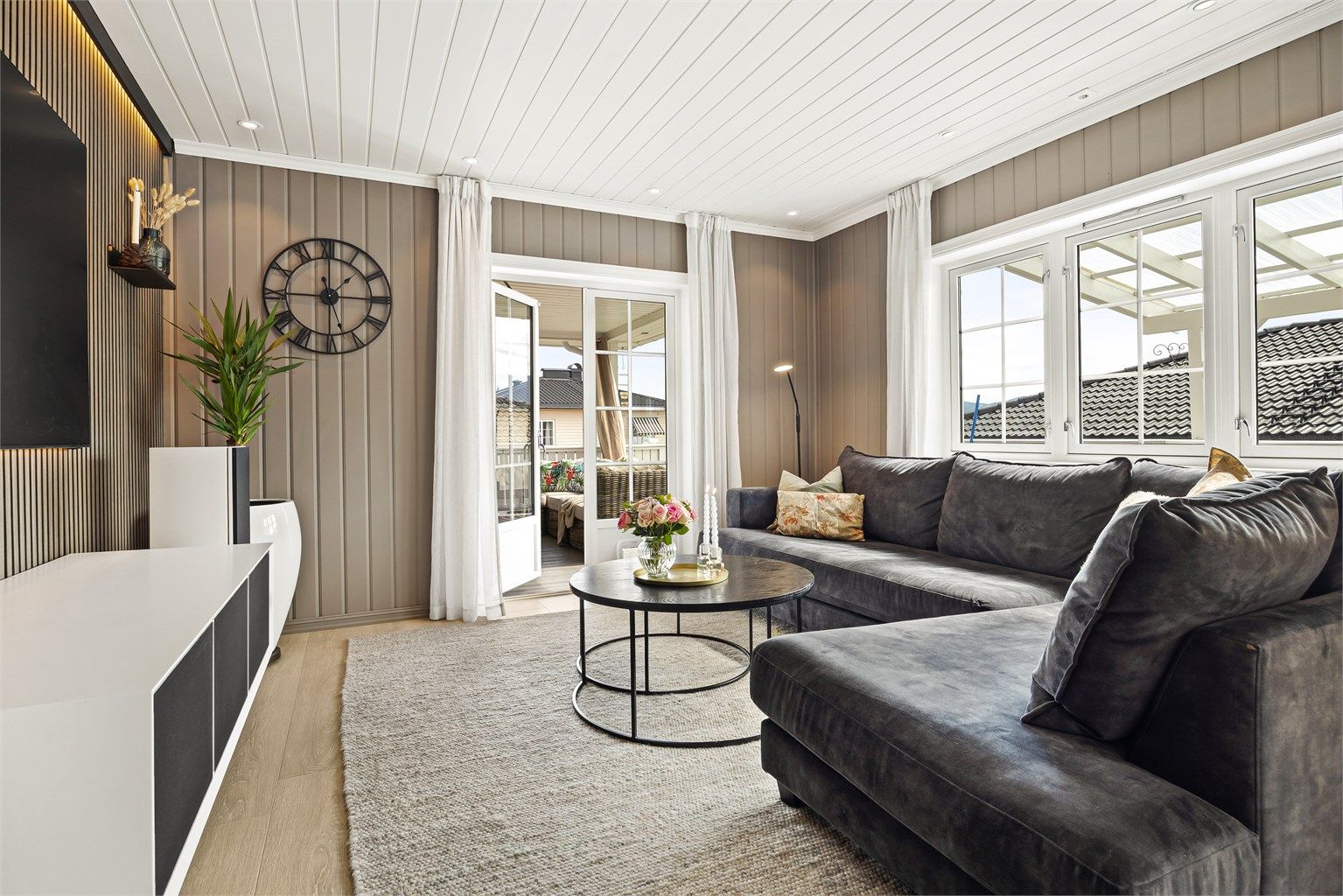 Moderne kontrastvegg med spiler og belysning ved sofaområder.
