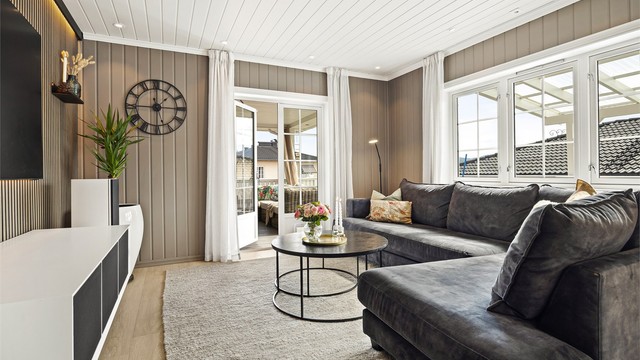 Moderne kontrastvegg med spiler og belysning ved sofaområder.
