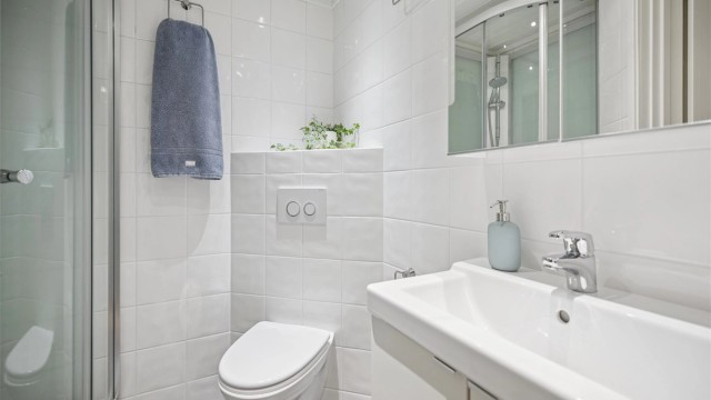 Pent flislagt bad med gulvvarme, vegghengt servantinnredning, dusjkabinett og vegghengt toalett.