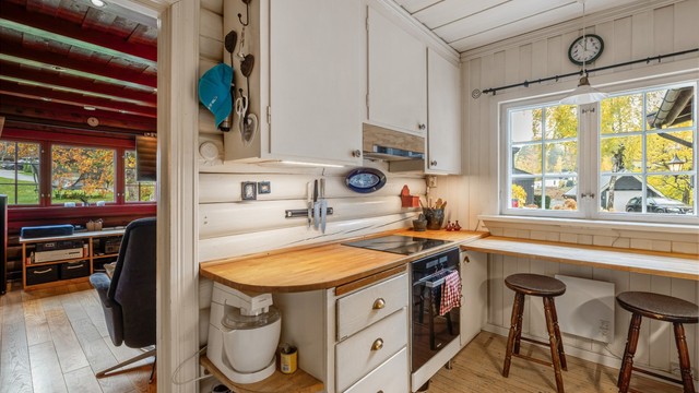 Kjøkkenet har original innredning fra byggeår med glatte fronter, benkeplate i heltre samt benkeplate i rustfritt stål med nedfelt oppvaskkum