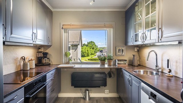 Kjøkkeninnredning med profilerte fronter og laminert benkeplate.