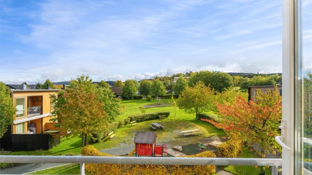 Balkongen har dekke av terrassebord og rekkverk i metall.