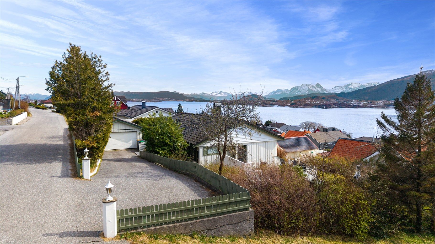 Asfaltert innkjørsel fører frem til en romslig gårdsplass med garasje og gode parkeringsmuligheter.