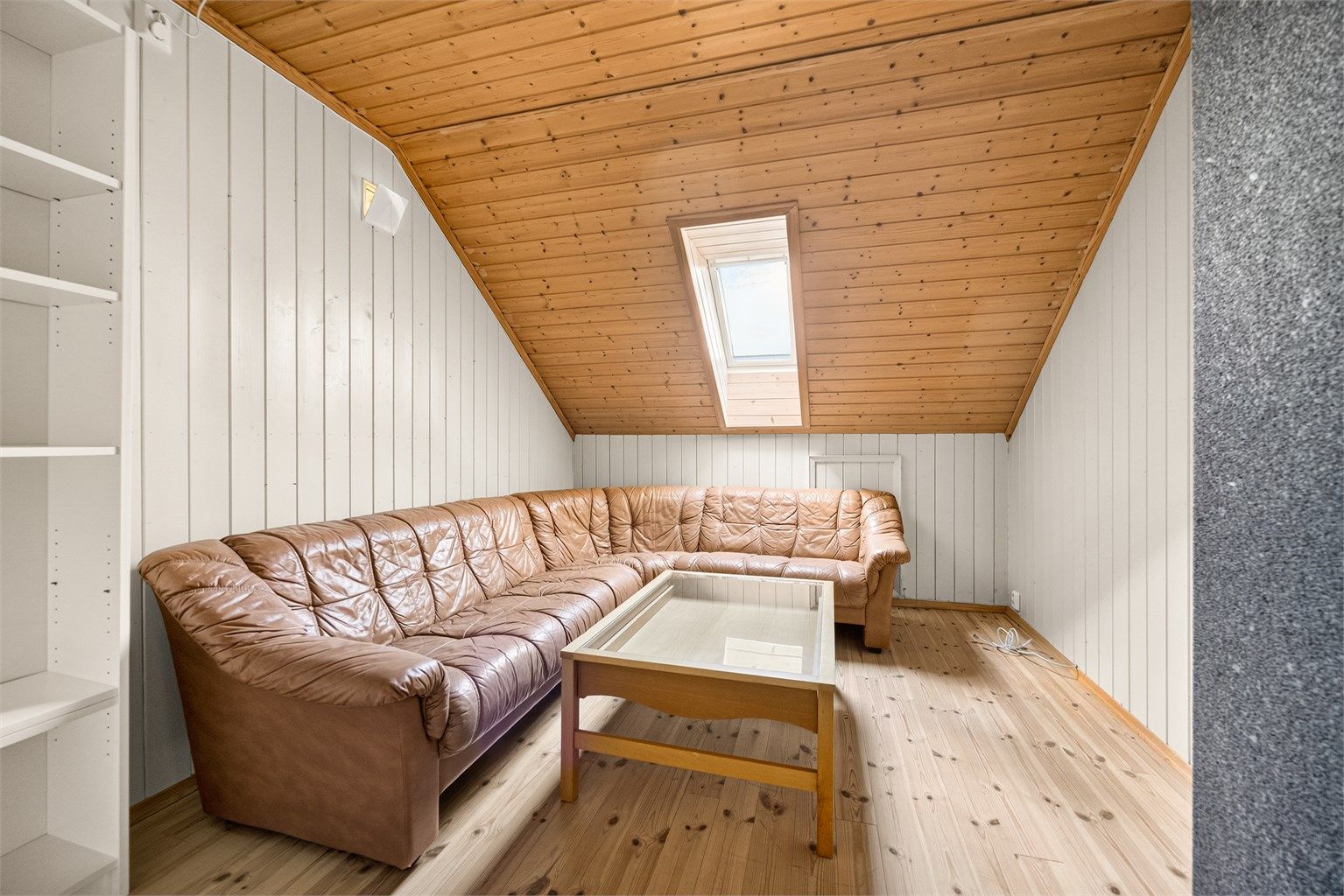 Innredet loftstue med takvindu og panel i taket.