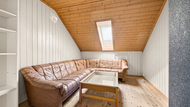 Innredet loftstue med takvindu og panel i taket.