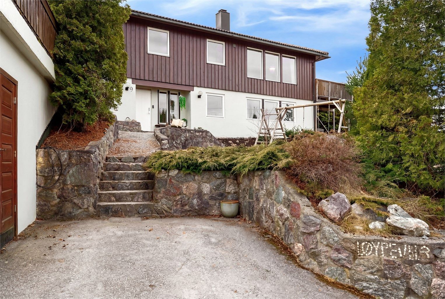 Trapp i naturstein leder opp til det overbygde inngangspartiet.