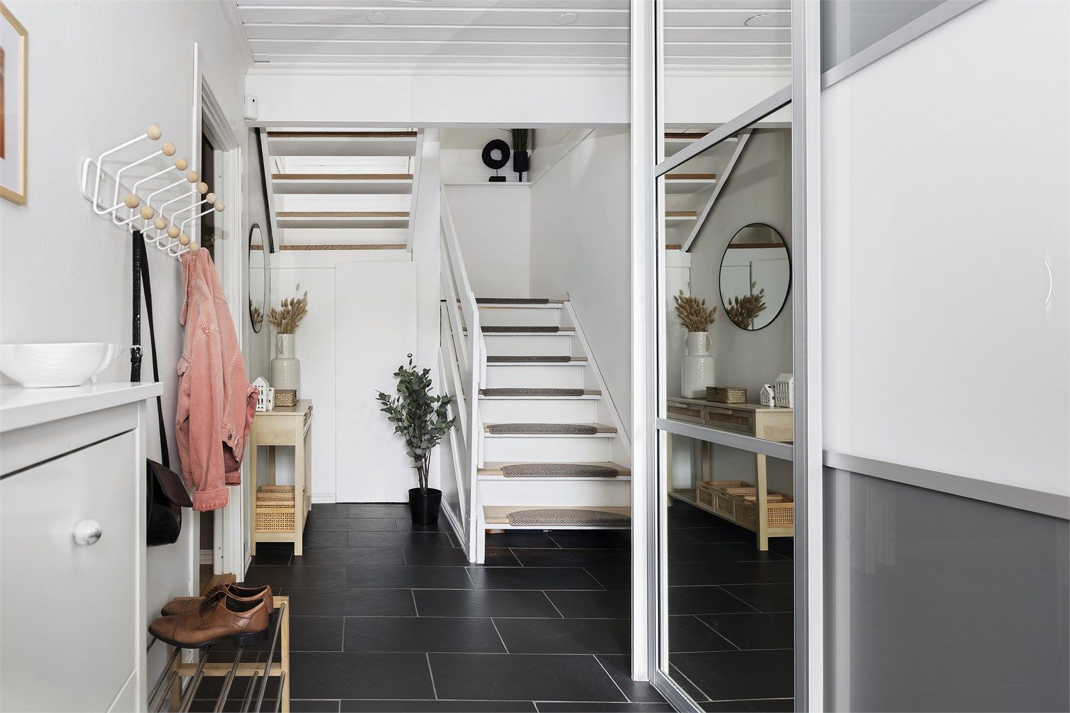 Entréen har flislagt gulv med varmekabler og stor skyvedørsgarderobe.