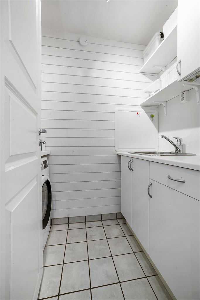 Vaskerom med fliser på gulvet og praktisk skap/hylle-system.