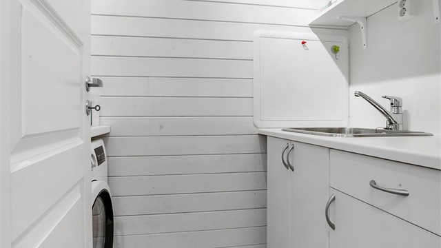 Vaskerom med fliser på gulvet og praktisk skap/hylle-system.