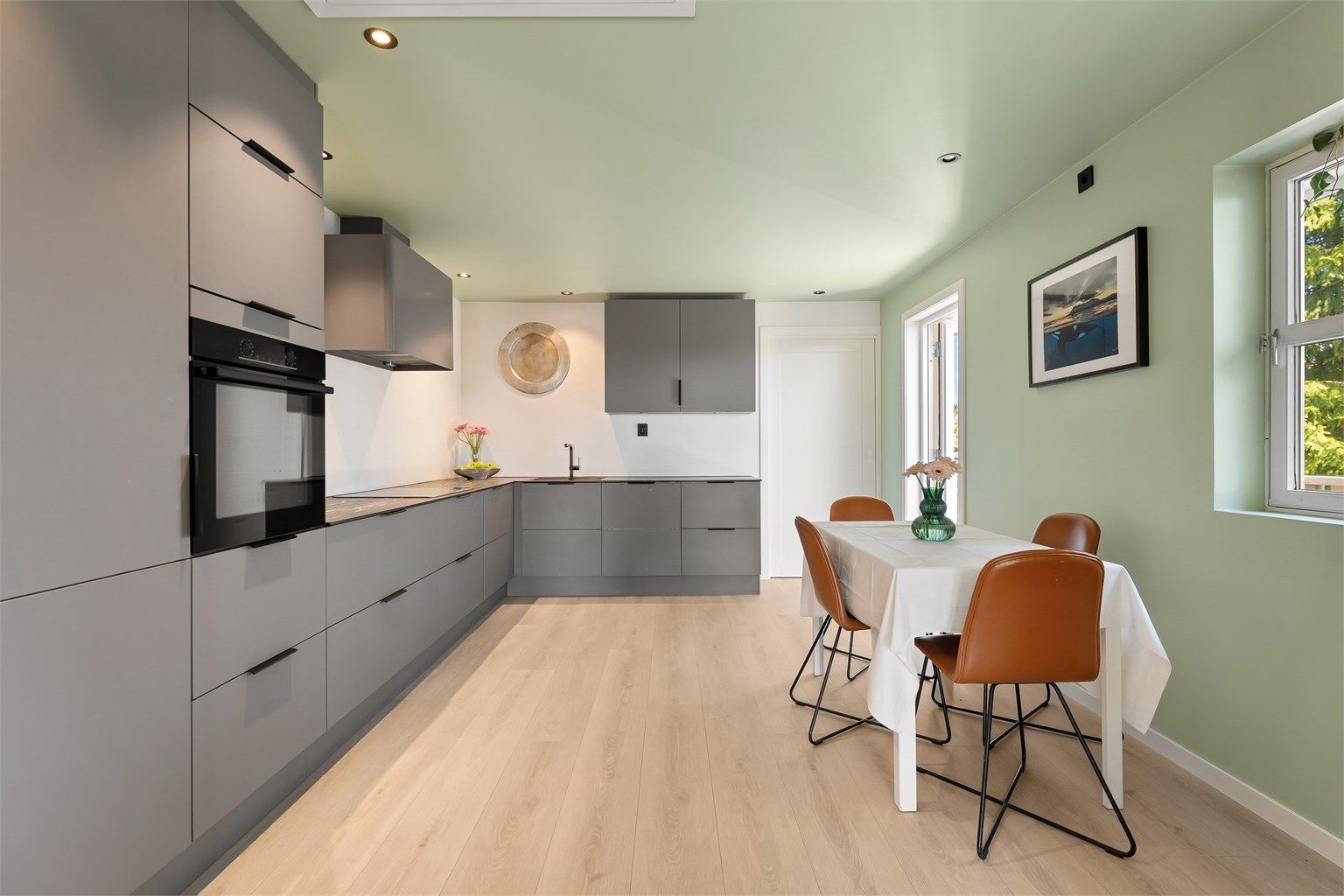 Kjøkkenet fra Aubo (2023) har glatte fronter, benkeplater i kompositt og downlights i himling.