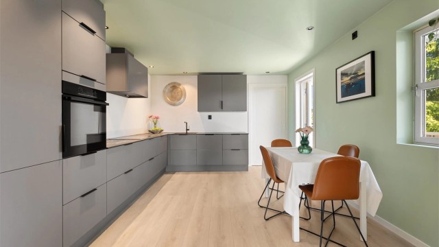 Kjøkkenet fra Aubo (2023) har glatte fronter, benkeplater i kompositt og downlights i himling.