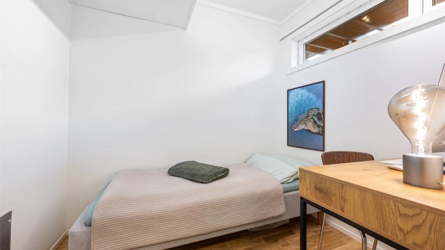 Innvendig bod har plass til både seng og kontor. Parkett på gulv og lyse veggflater og tak. Det er lite vindu som kan åpnes.