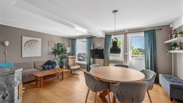 Stue i hovedpan med parkettgulv, peisovn og direkte utgang til veranda.