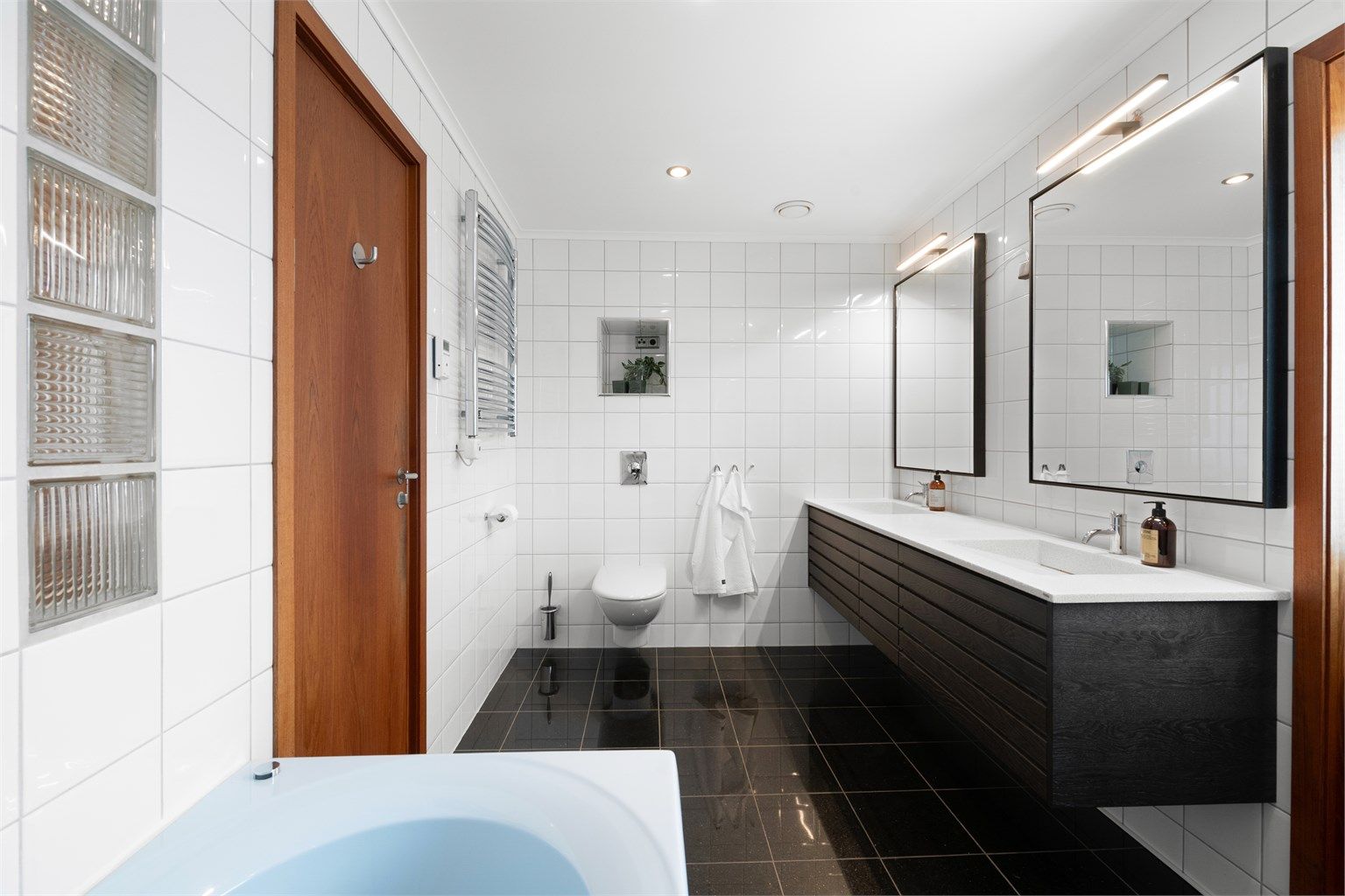 Badet mot syd har dobbel servant med mørk baderomsinnredning, speil med overlys og gulvvarme.