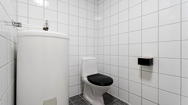 Flislagt bad med funksjonell planløsning og nøytrale overflater.