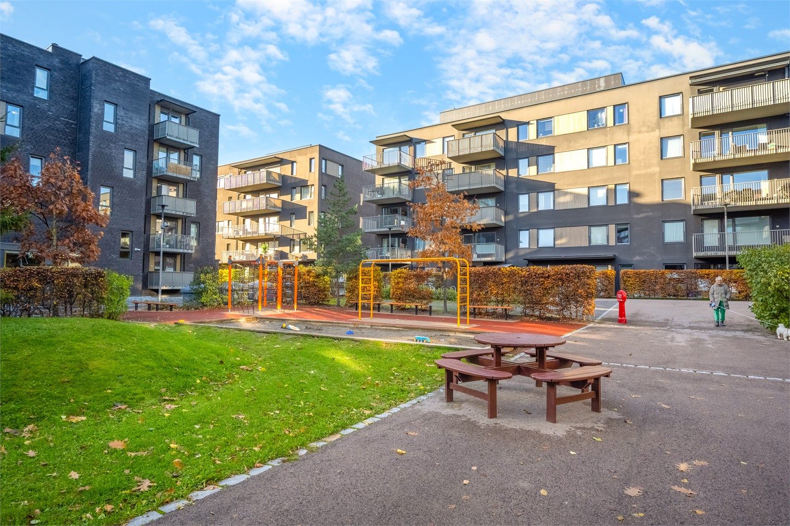 Skjermet fellesareal med lekeplass og sittegrupper i et trygt bomiljø.