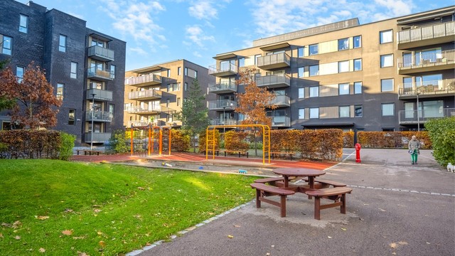 Skjermet fellesareal med lekeplass og sittegrupper i et trygt bomiljø.