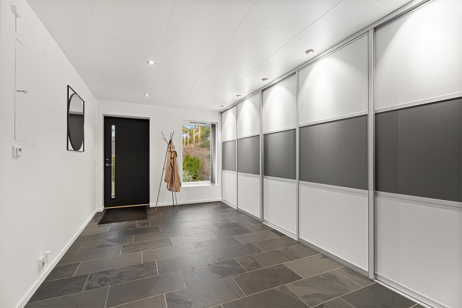 Innbydende og romslig entre med Langlo skyvedørsgraderobe med Elfa garderobesystem.