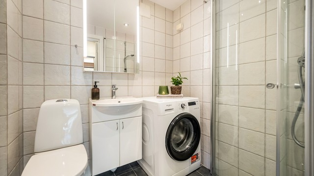 Et praktisk og lyst bad med servant i baderomsseksjon, speilskap og opplegg for vaskemaskin, og med deilig varme gulv hele året.