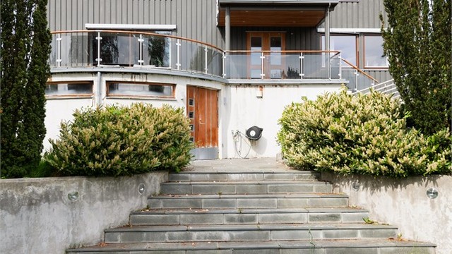 Skiferbelagte trappetrinn fører opp til den buede terrassen utenfor stuen.