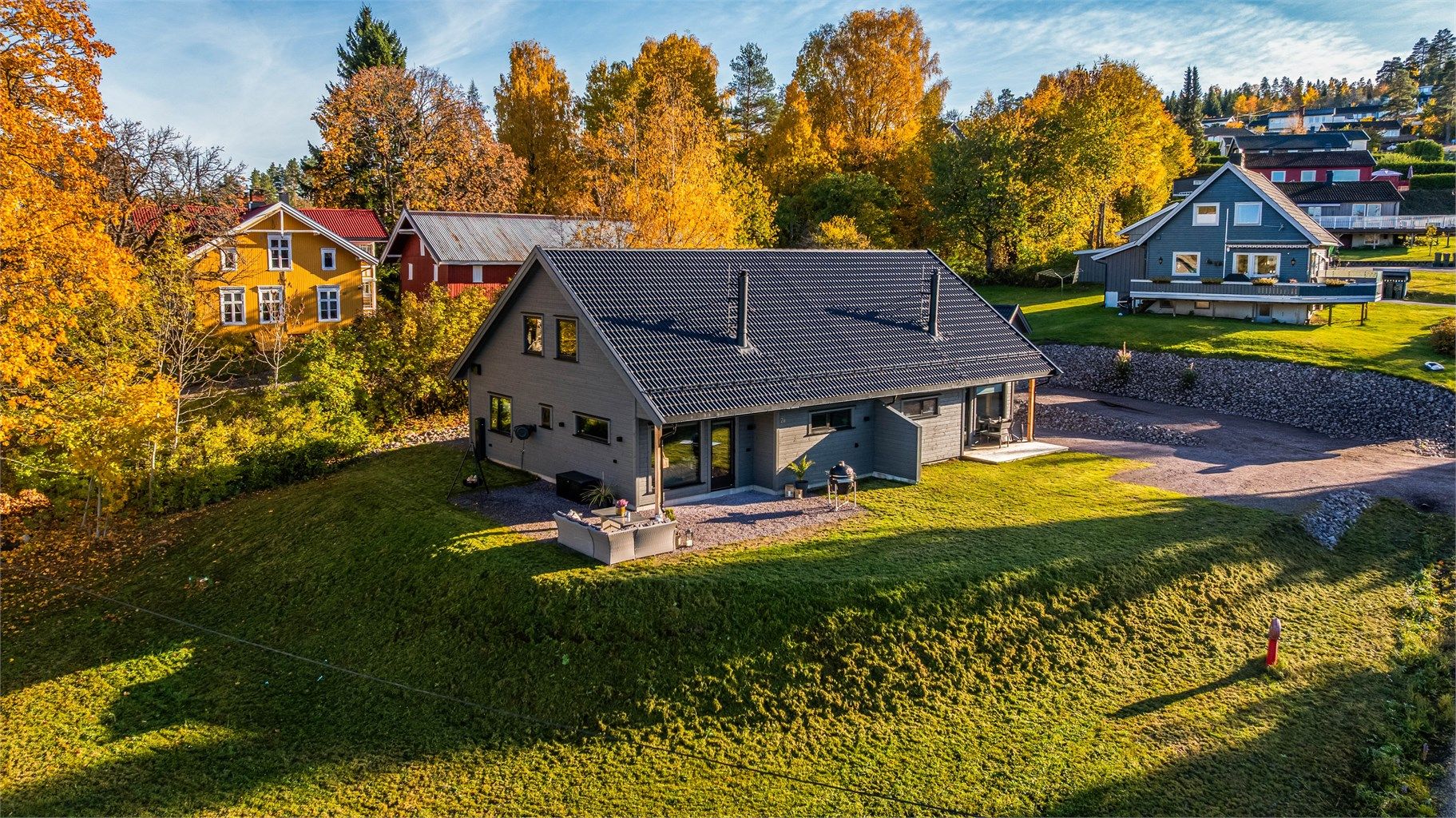 Romslig tomt med plenarealer og gruset innkjørsel.