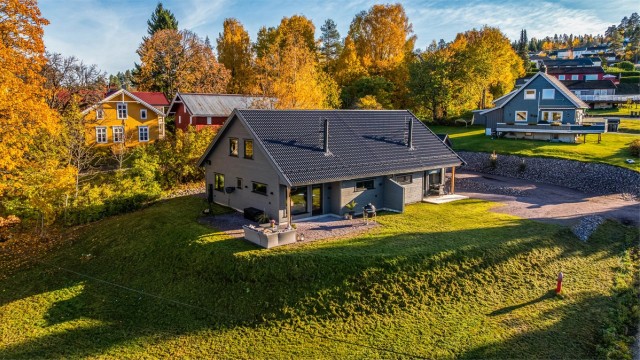 Romslig tomt med plenarealer og gruset innkjørsel.