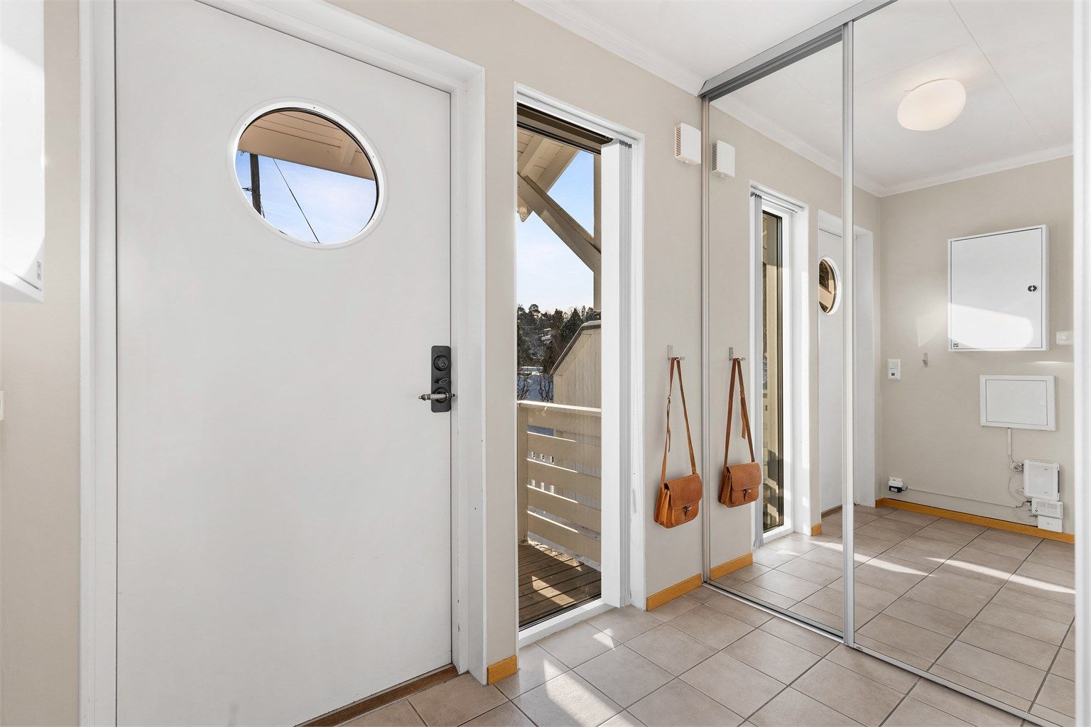 Entré med fliser på gulv og skyvedørsgarderobe.