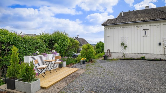 Romslig gårdsplass hvor hver seksjon har én biloppstillingsplass lags husveggen