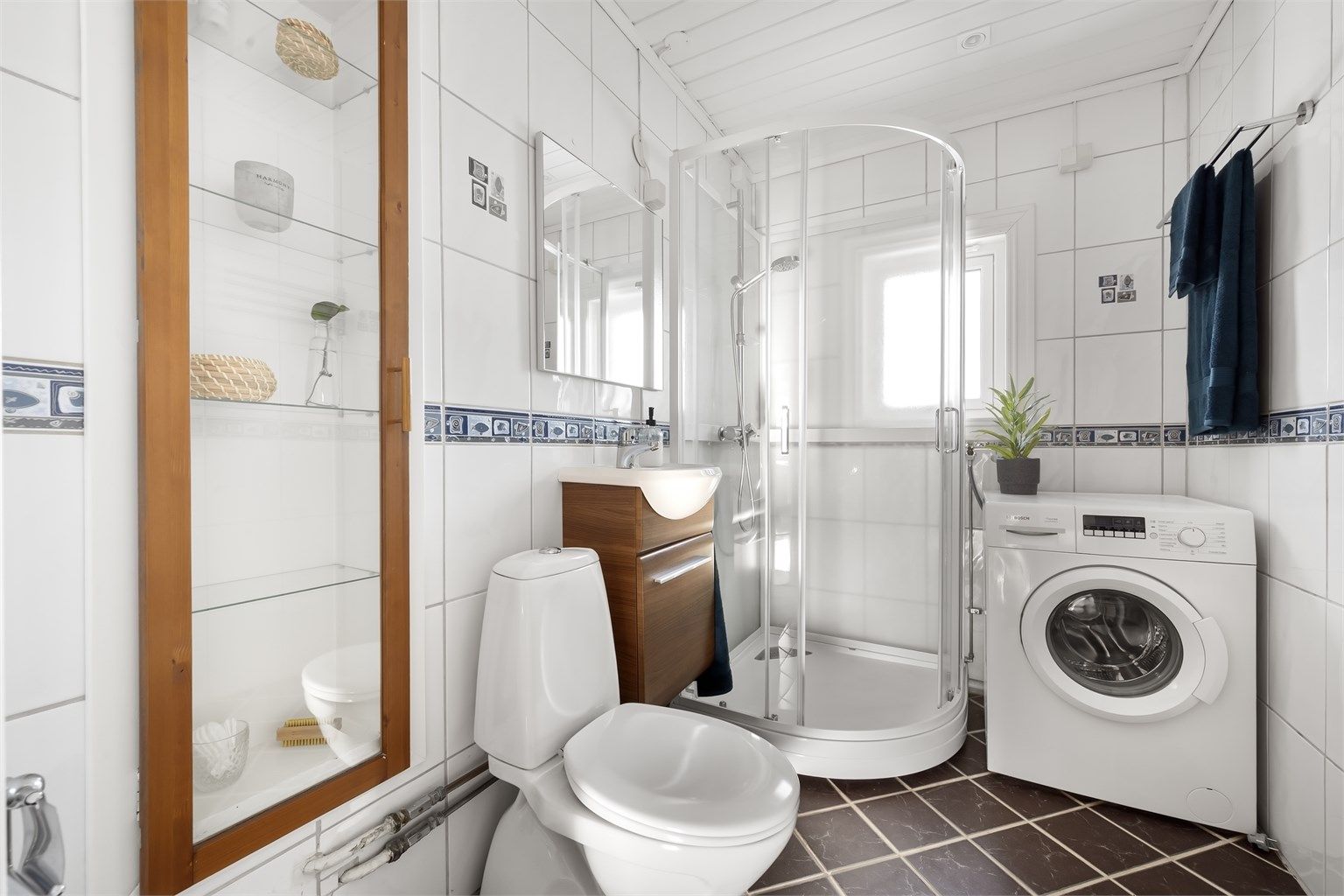 Flislagt bad med gulvvarme, dusjkabinett og opplegg for vaskemaskin.