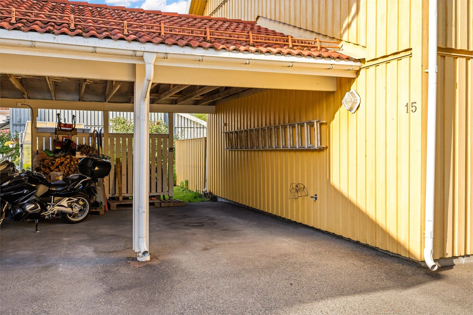 Tilliggende carport med asfaltert gulv og plass til én bil.