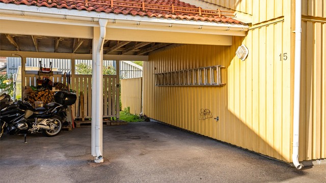 Tilliggende carport med asfaltert gulv og plass til én bil.