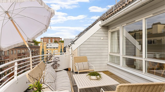 Takterrassen er en naturlig forlengelse av boligen, med tregulv på tilfarere og rekkverk i stål, betong og glass – her er det lett å bli sittende utover kvelden.