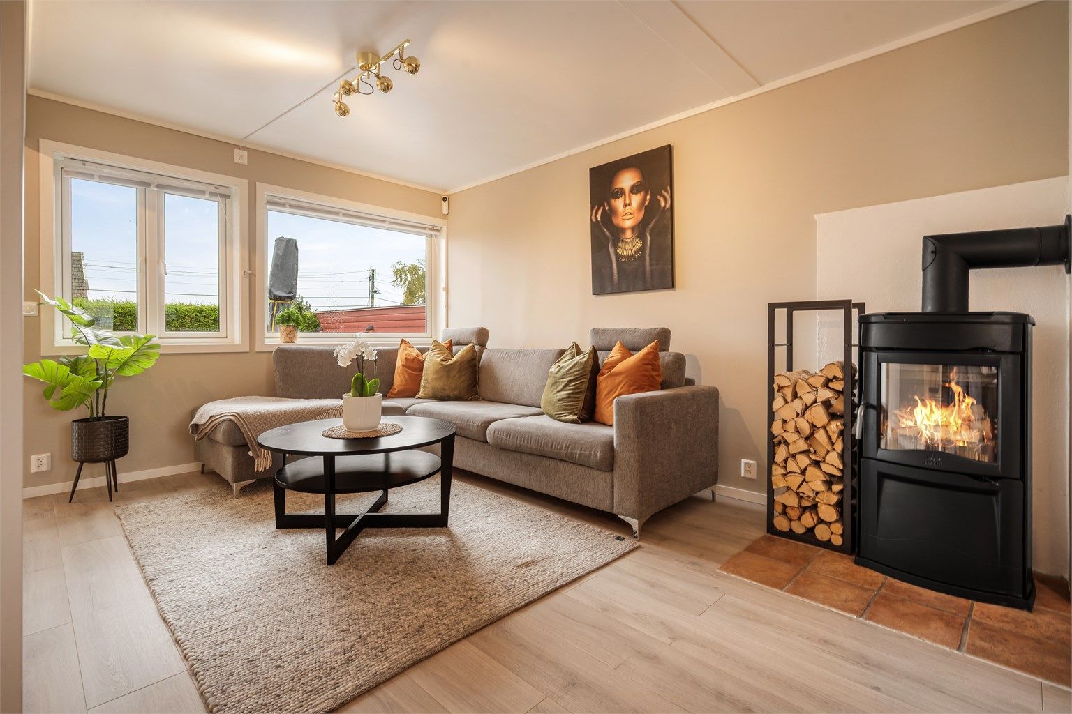 Lyse og delikate fargetoner gir stuen et lunt og harmonisk uttrykk, med peisovn og god plass til en stor sofagruppe.
