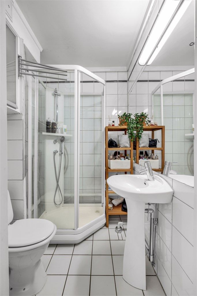 Lyst, flislagt baderom med dusj, toalett og servant.