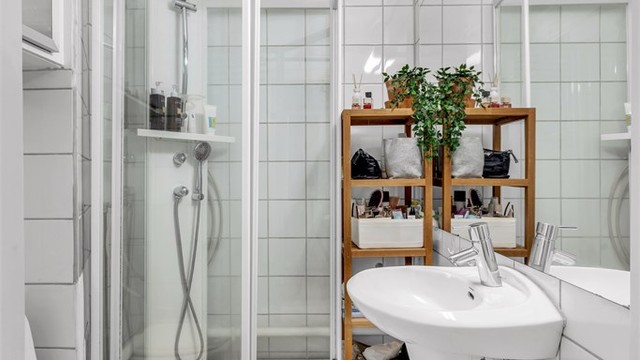 Lyst, flislagt baderom med dusj, toalett og servant.