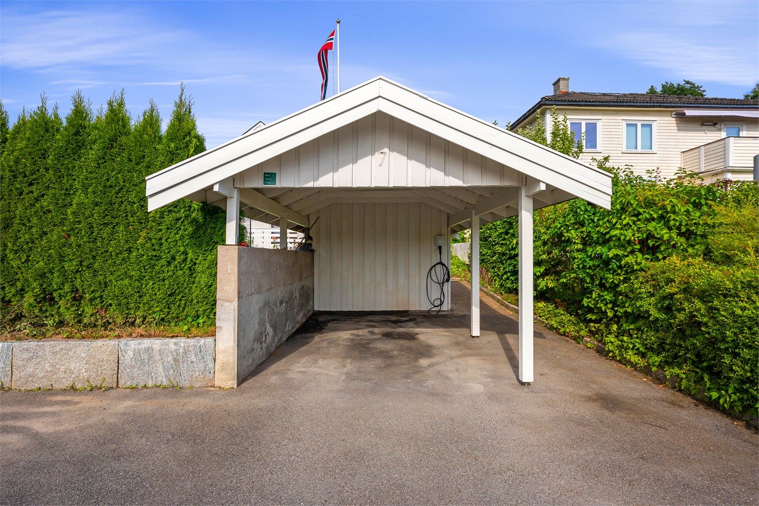 Carport med installert elbillader og tilhørende bod.