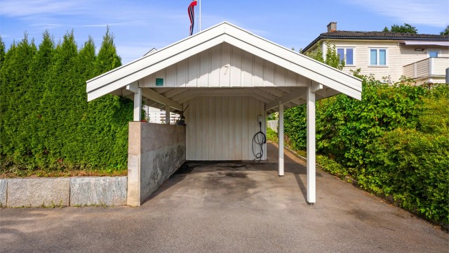 Carport med installert elbillader og tilhørende bod.
