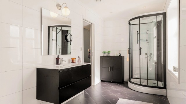 Badet i første etasje har flislagt gulv med varme, vegghengt toalett og dusjkabinett.