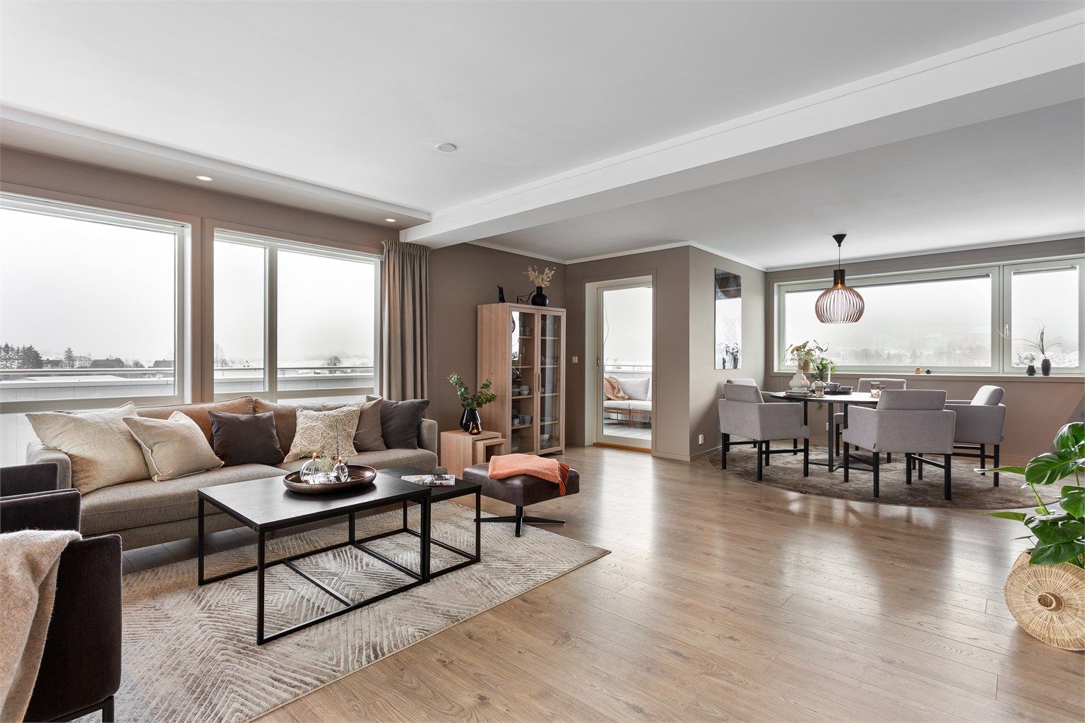 Romslig og lekker stue med store vindusflater, fra tre sider, som gir mye naturlig lys