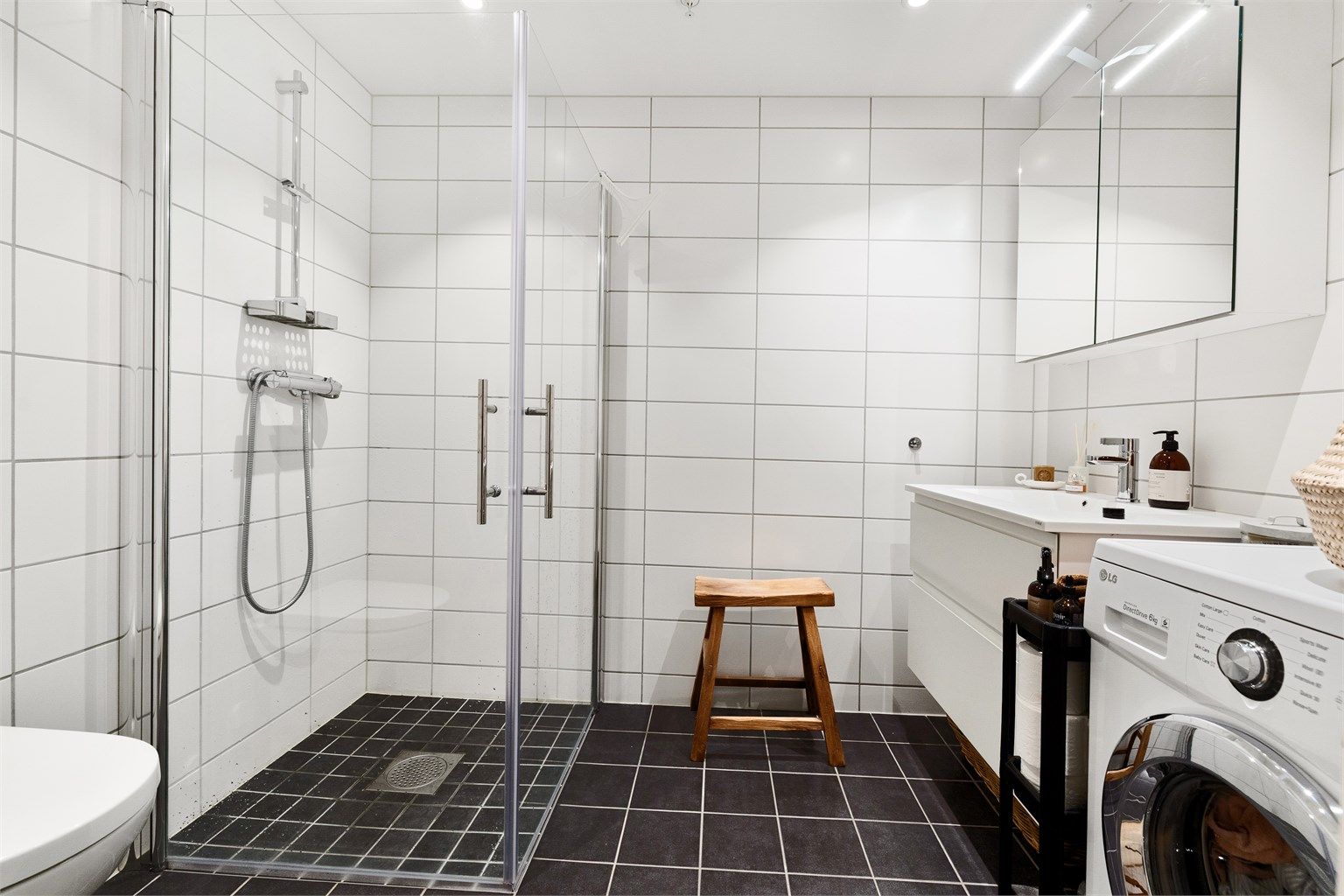 Moderne, flislagt bad fra 2023 med gulvvarme, downlights, vegghengt toalett og opplegg for vaskemaskin.