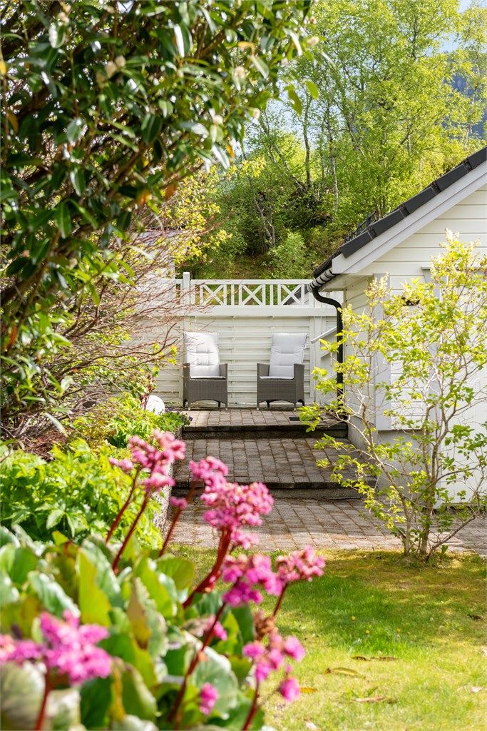 Uteplassen er omkranset av frodig hage og beplantning.