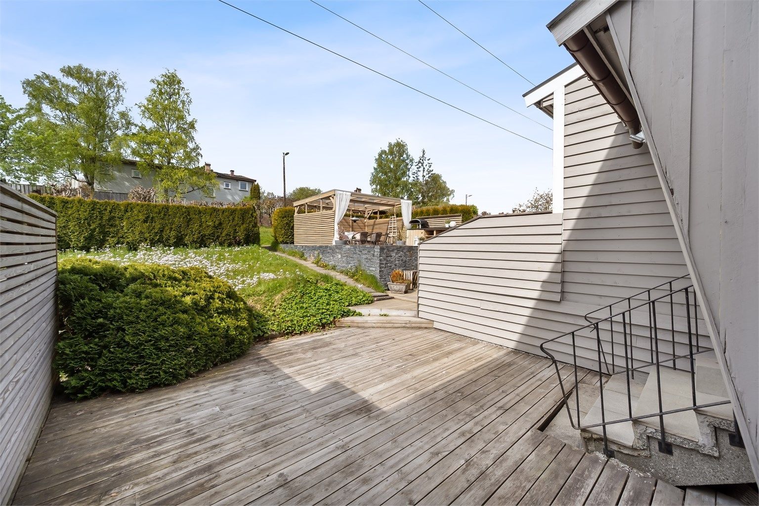 Terrassen er belagt med terrassebord og skjermet med levegger i tre.